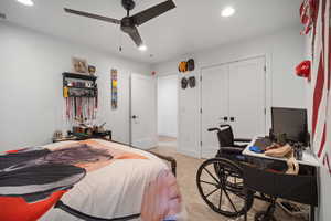 Bedroom with light colored carpet, a desk, recessed lighting, ceiling fan, and a closet