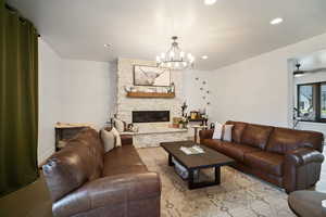 Living room featuring wood finished floors, a chandelier, recessed lighting, a stone fireplace, and a ceiling fan