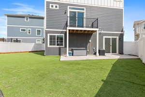 Rear view of property featuring a patio area, a fenced backyard, and a balcony