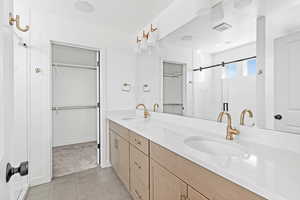 Full bath featuring a walk in closet, double vanity, a stall shower, and tile patterned flooring