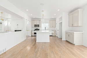 Kitchen with white electric range oven, stainless steel microwave, light countertops, light wood-type flooring, and recessed lighting