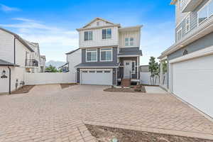 View of front facade with board and batten siding, decorative driveway, and a garage