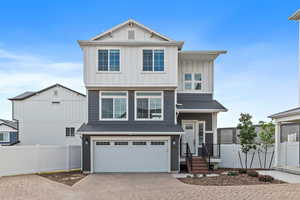 View of front of home with board and batten siding, decorative driveway, a garage, and a shingled roof