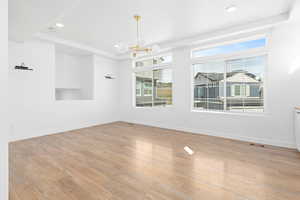 Unfurnished room featuring a chandelier, recessed lighting, light wood-style flooring, a tray ceiling, and a smoke detector