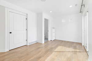 Unfurnished bedroom with light wood-style flooring, recessed lighting, and connected bathroom