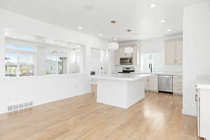 Kitchen with appliances with stainless steel finishes, healthy amount of natural light, light wood-style floors, light countertops, and recessed lighting