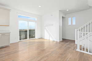 Unfurnished living room featuring light wood finished floors, recessed lighting, and stairway