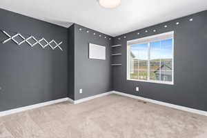 Carpeted spare room featuring baseboards