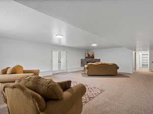 Carpeted living area featuring a baseboard heating unit, french doors, and a textured ceiling