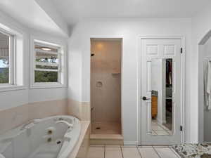Bathroom featuring a shower stall, a jetted tub, and tile patterned floors
