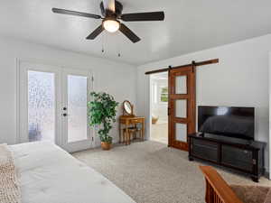 Bedroom with a barn door, access to exterior, carpet floors, connected bathroom, and ceiling fan