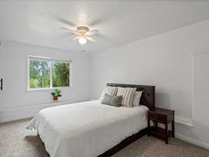 Carpeted bedroom with ceiling fan and baseboards