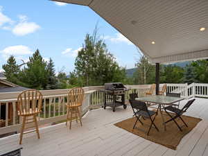Wooden terrace featuring grilling area and outdoor dining space