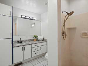 Bathroom with a marble finish shower, vanity, and tile patterned flooring