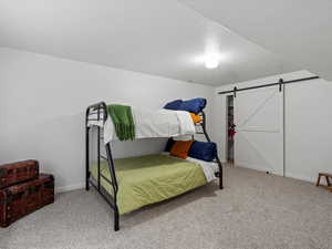 Carpeted bedroom with a barn door and a textured ceiling
