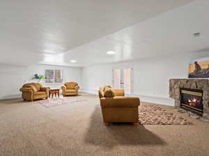 Carpeted living area with a fireplace, a textured ceiling, french doors, and recessed lighting
