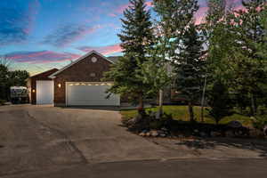 View of front facade featuring driveway, an attached garage, a lawn, and brick siding