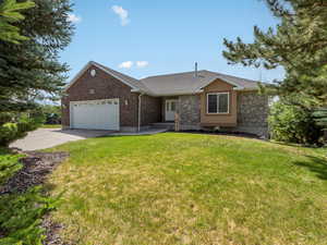Single story home featuring a garage, driveway, stone siding, a front yard, and roof with shingles