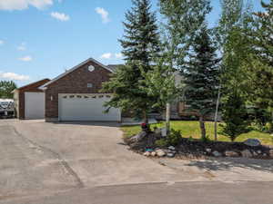 View of front facade with a garage, a front yard, brick siding, and driveway