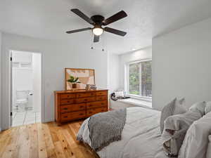 Bedroom with light wood-style floors, connected bathroom, and ceiling fan