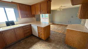 Kitchen featuring white dishwasher, brown cabinetry, healthy amount of natural light, and a textured ceiling