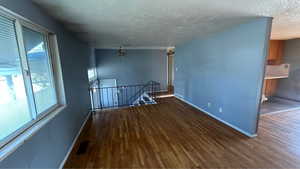 Unfurnished room featuring a textured ceiling, wood finished floors, and ceiling fan