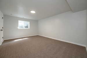 Unfurnished room with baseboards and dark colored carpet