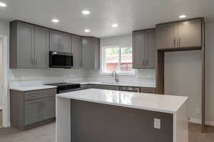 Kitchen with stainless steel microwave, gray cabinets, black electric range oven, recessed lighting, and light countertops