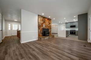 Unfurnished living room with wood finished floors, recessed lighting, and a wood stove