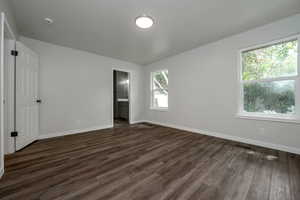 Unfurnished bedroom featuring dark wood-type flooring and ensuite bath