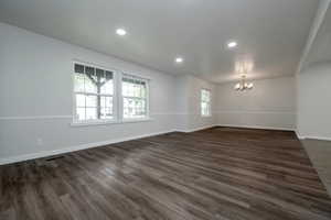 Unfurnished room featuring a chandelier, dark wood-style flooring, and recessed lighting