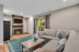 Living room featuring wood finished floors, a fireplace, and recessed lighting