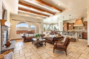 Living room with beamed ceiling, stone tile floors, a fireplace, and recessed lighting