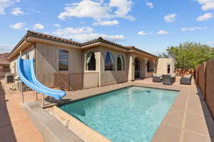 Back of property featuring an outdoor hangout area, a patio area, stucco siding, a tile roof, and a fenced backyard