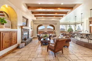 Living area with stone tile floors, beamed ceiling, a fireplace, and recessed lighting