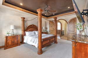 Bedroom with a tray ceiling, arched walkways, light carpet, recessed lighting, and a ceiling fan