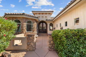 Property entrance featuring stone siding, a tile roof, french doors, and stucco siding