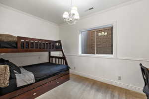 Bedroom with wainscoting, crown molding, carpet flooring, a chandelier, and wood walls