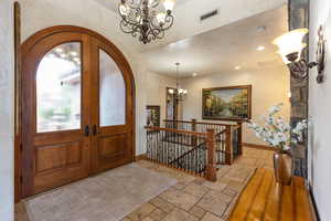 Foyer with a chandelier, stone tile floors, and french doors