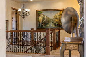 Staircase with stone tile flooring and a chandelier