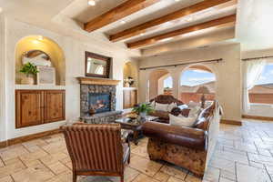 Living room featuring stone tile floors, beamed ceiling, recessed lighting, and a fireplace