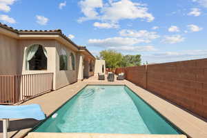 View of swimming pool featuring patio surround, a fenced backyard, and outdoor furniture
