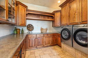 Laundry area with stone tile flooring, cabinet space, and separate washer and dryer