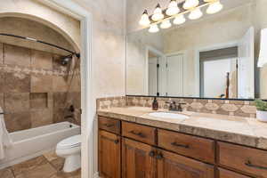 Full bath with shower / bath combo with shower curtain, vanity, and backsplash