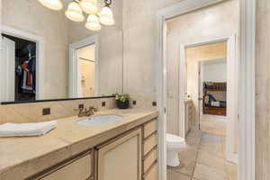 Bathroom with vanity, tasteful backsplash, a spacious closet, and stone tile flooring