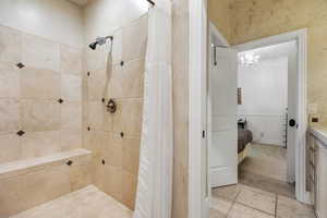 Ensuite bathroom with a tile shower, vanity, and a chandelier