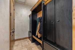 Mudroom featuring stone tile flooring and baseboards