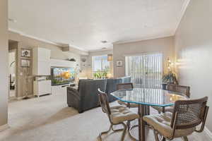 Dining space with light carpet and crown molding