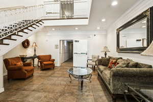 Living room featuring crown molding, recessed lighting, and stairs