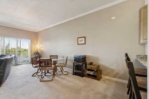 Dining space with carpet floors and crown molding